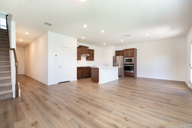 kitchen with a center island with sink, stainless steel appliances, sink, and light hardwood / wood-style flooring