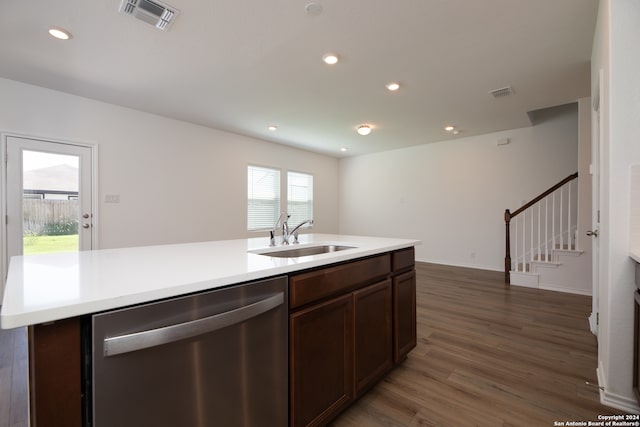 kitchen featuring an island with sink, dark hardwood / wood-style flooring, dark brown cabinets, stainless steel dishwasher, and sink