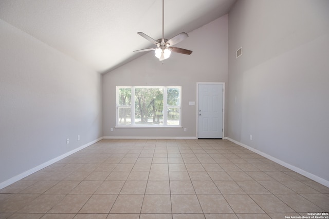 tiled empty room with ceiling fan and high vaulted ceiling