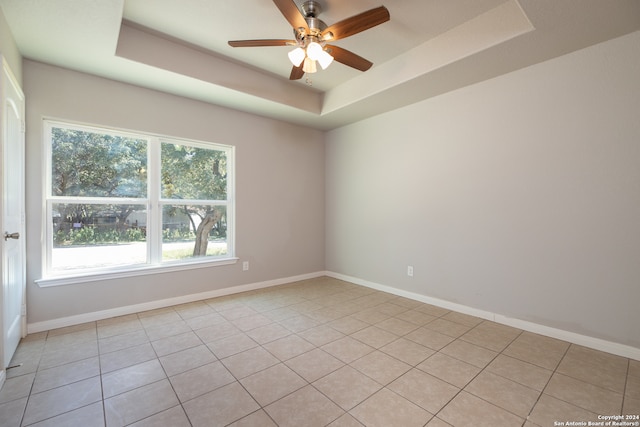 spare room with light tile patterned floors, a tray ceiling, and ceiling fan