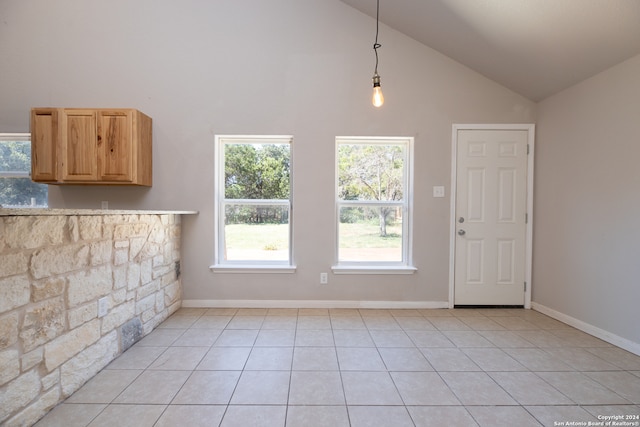 unfurnished dining area featuring light tile patterned floors and high vaulted ceiling