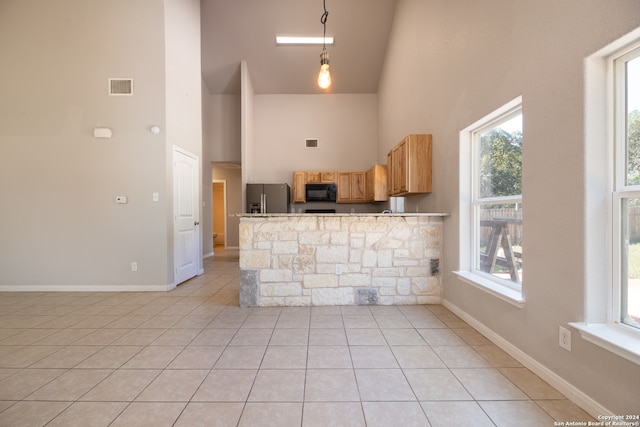 kitchen with hanging light fixtures, stainless steel fridge, high vaulted ceiling, kitchen peninsula, and light tile patterned floors