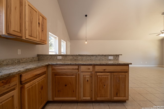 kitchen featuring light stone counters, pendant lighting, light tile patterned floors, lofted ceiling, and ceiling fan