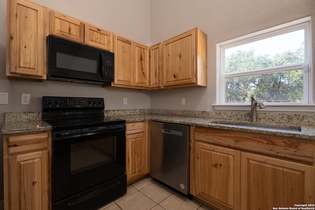 kitchen featuring light tile patterned floors, light stone countertops, sink, and black appliances