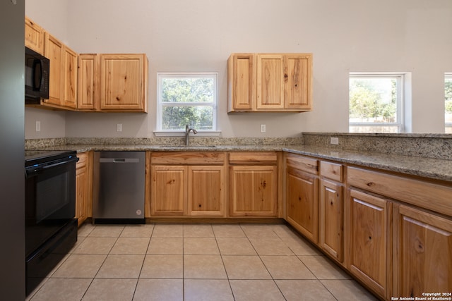 kitchen featuring black appliances, light stone countertops, and a wealth of natural light