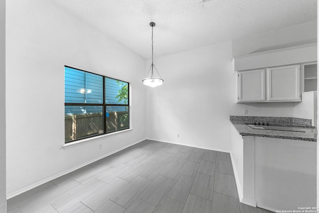 kitchen with white cabinets, a textured ceiling, decorative light fixtures, and light hardwood / wood-style floors