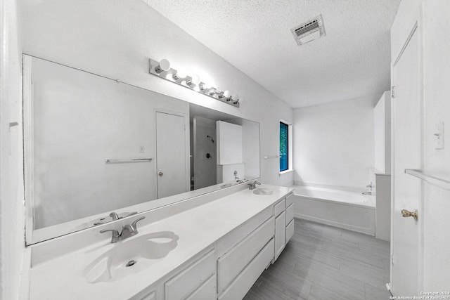 bathroom with a tub, vanity, and a textured ceiling