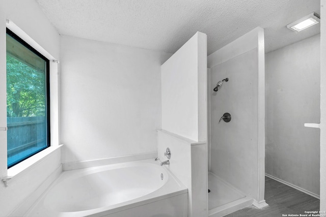 bathroom with hardwood / wood-style floors, a textured ceiling, and shower with separate bathtub