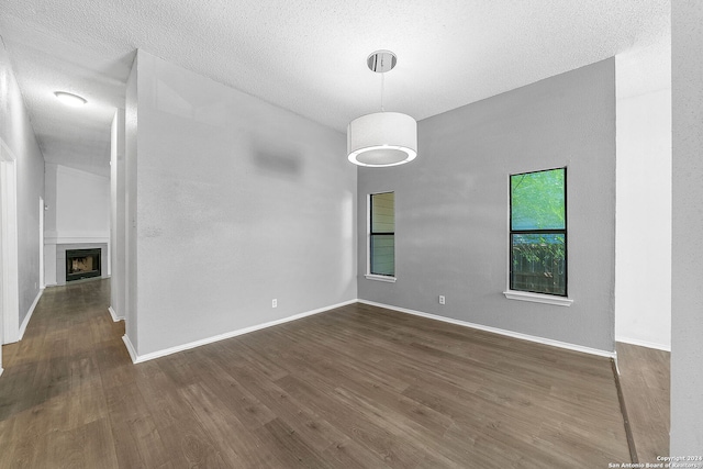 empty room with dark hardwood / wood-style flooring and a textured ceiling