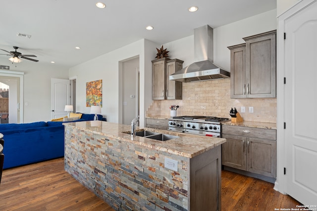 kitchen featuring stainless steel range oven, dark hardwood / wood-style floors, wall chimney range hood, and light stone countertops