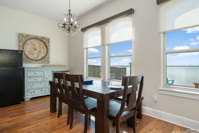 dining area featuring an inviting chandelier, hardwood / wood-style flooring, and a water view