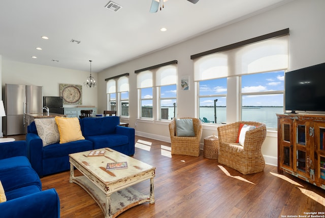 living room with ceiling fan with notable chandelier and dark hardwood / wood-style flooring