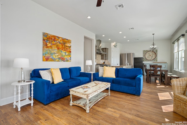 living room with light hardwood / wood-style flooring and ceiling fan with notable chandelier