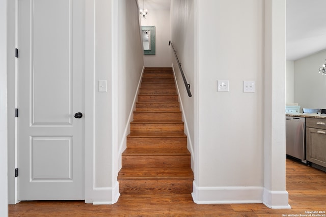 stairway featuring a notable chandelier and wood-type flooring