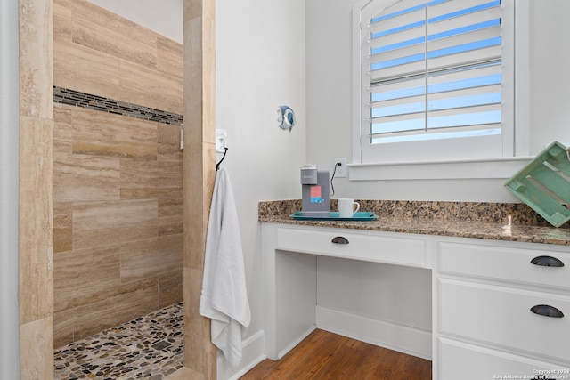 bathroom featuring hardwood / wood-style flooring, vanity, and tiled shower