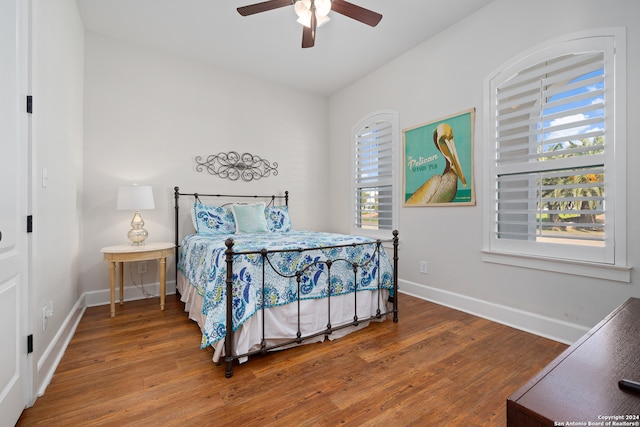 bedroom with multiple windows, ceiling fan, and hardwood / wood-style flooring