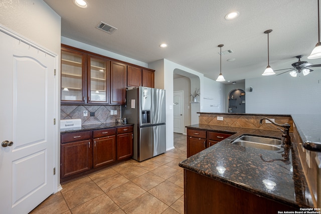 kitchen featuring ceiling fan, sink, hanging light fixtures, backsplash, and stainless steel fridge