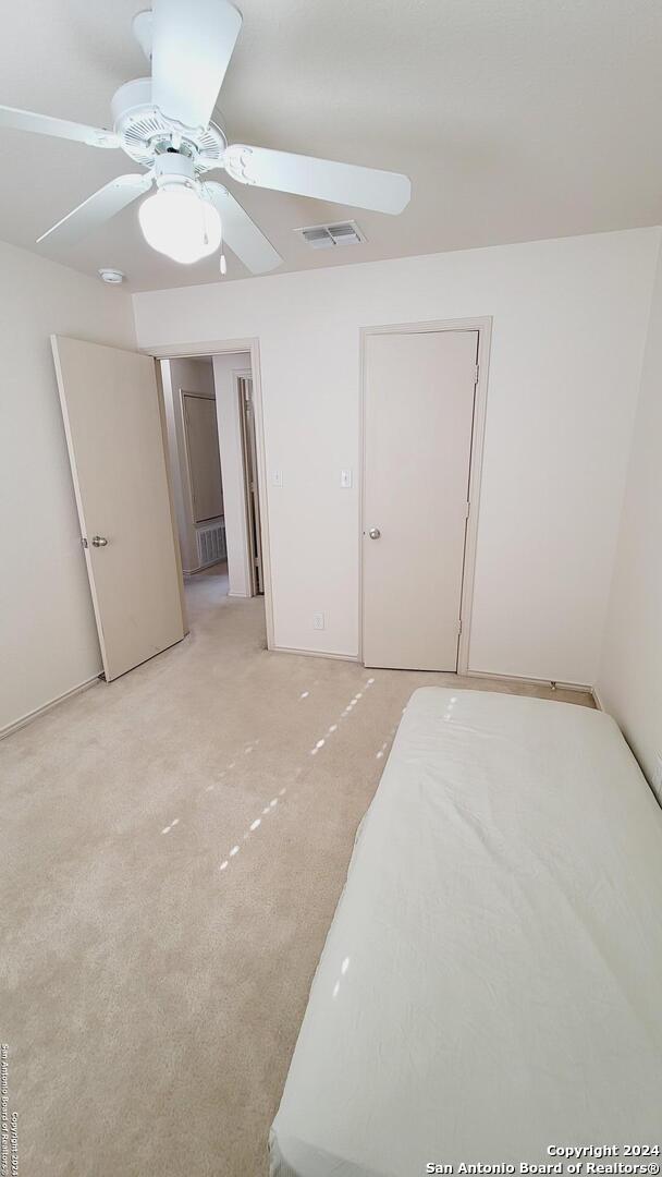 unfurnished bedroom featuring ceiling fan, a closet, and light carpet