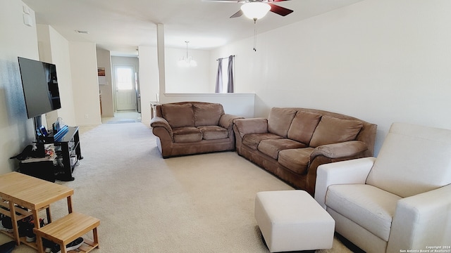 carpeted living room featuring ceiling fan with notable chandelier