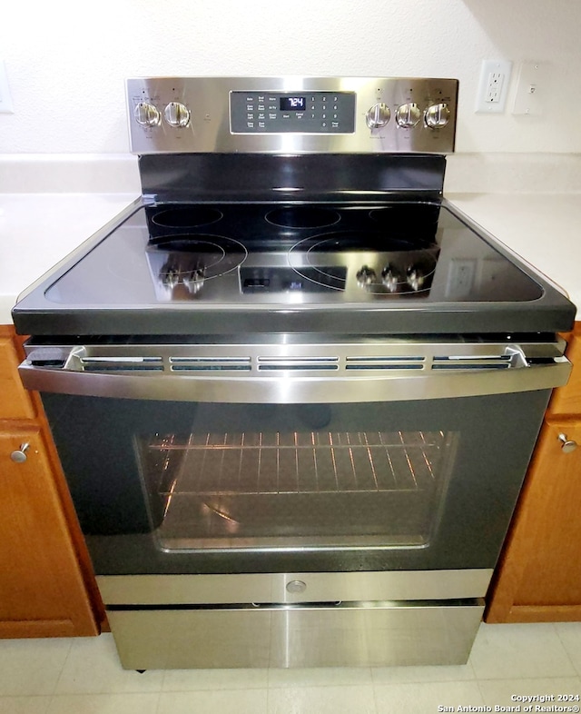 room details with stainless steel electric range and light tile patterned floors