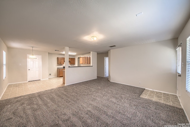 unfurnished living room featuring light carpet and plenty of natural light