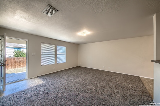 empty room with carpet and a textured ceiling