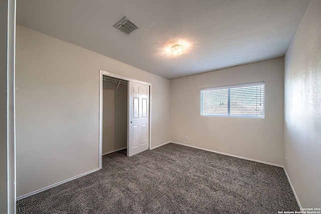 unfurnished bedroom with a closet and dark colored carpet