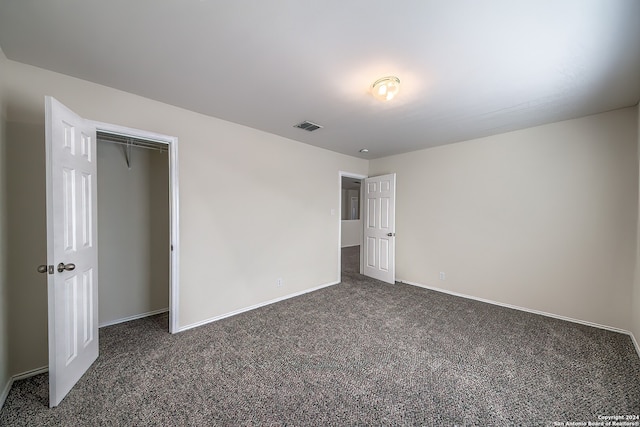 unfurnished bedroom featuring a closet and dark colored carpet