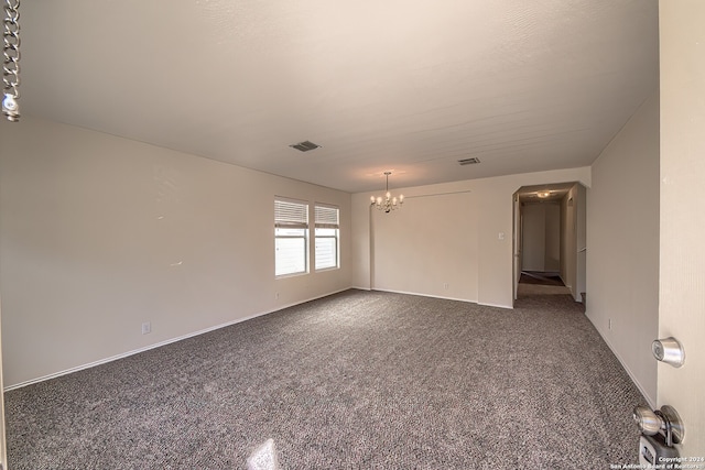 carpeted empty room with a notable chandelier