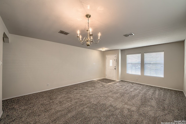 carpeted spare room with a chandelier