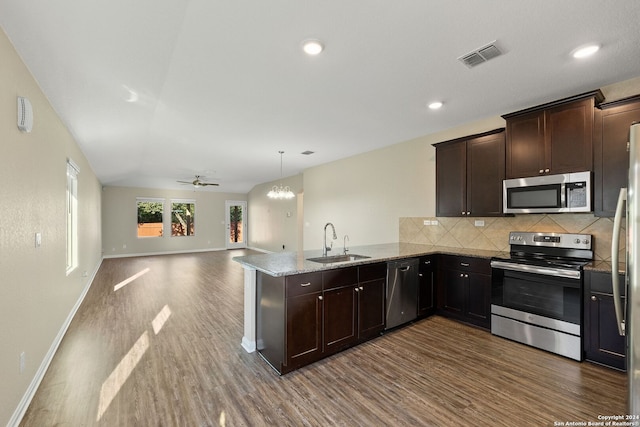 kitchen with ceiling fan with notable chandelier, kitchen peninsula, stainless steel appliances, hardwood / wood-style floors, and sink