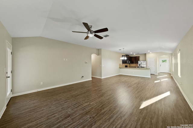 unfurnished living room featuring ceiling fan with notable chandelier, vaulted ceiling, and dark hardwood / wood-style flooring