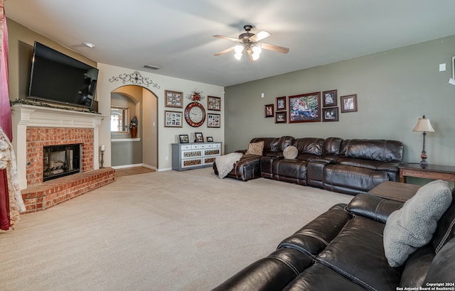 living room with ceiling fan, light colored carpet, and a brick fireplace