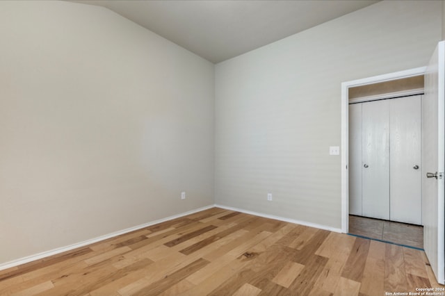 unfurnished bedroom with vaulted ceiling, light wood-style flooring, and baseboards