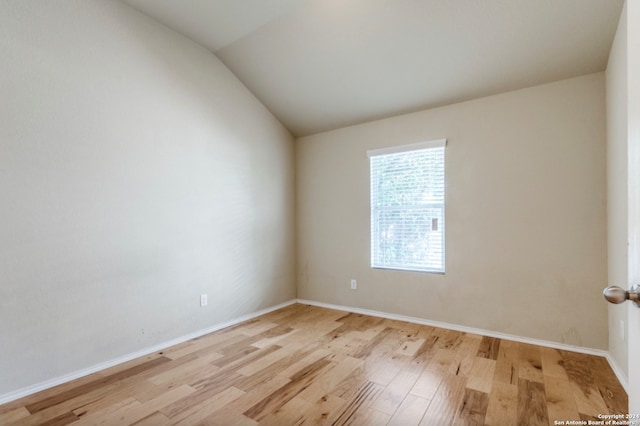 unfurnished room with light wood-style floors, baseboards, and vaulted ceiling