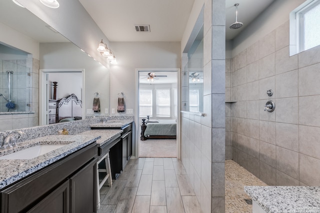 bathroom with ceiling fan, vanity, and tiled shower