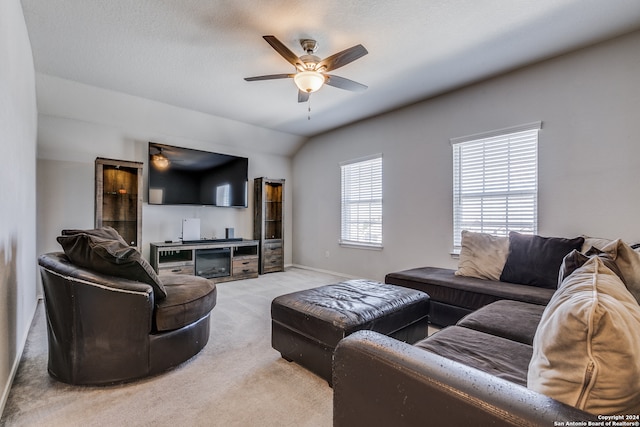 living room featuring vaulted ceiling, ceiling fan, light colored carpet, and a textured ceiling