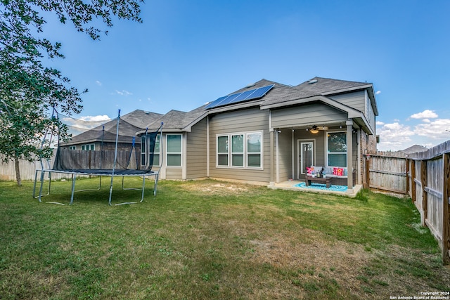 rear view of property with a lawn, a trampoline, and a patio area