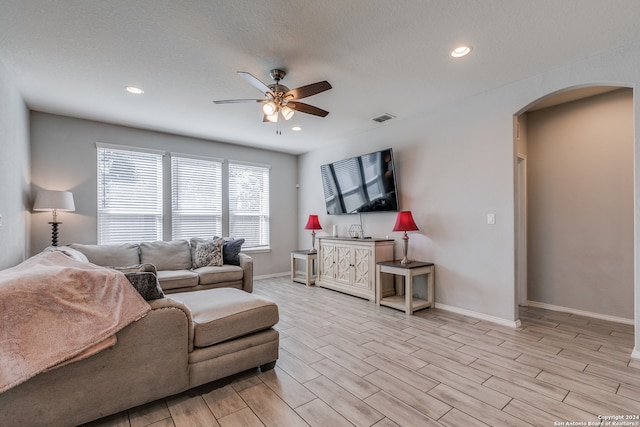 living room with ceiling fan, a textured ceiling, and light hardwood / wood-style floors