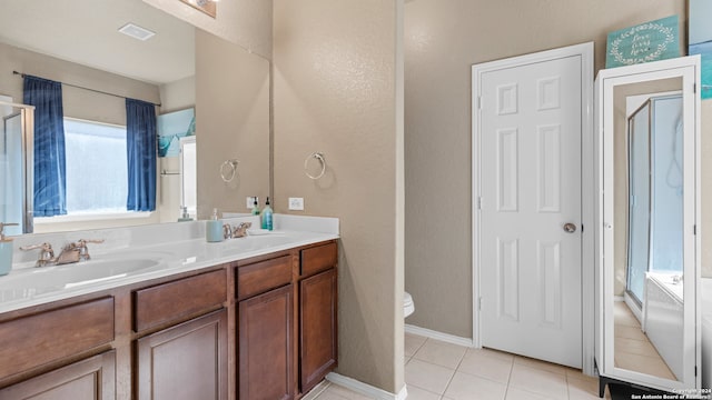 bathroom featuring tile patterned floors, vanity, toilet, and a shower with door