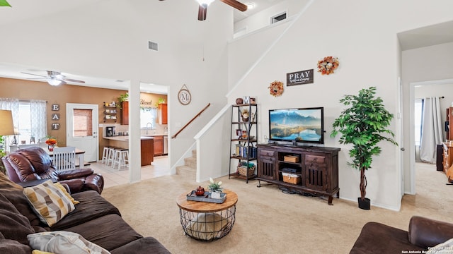 living room featuring light carpet, a high ceiling, ceiling fan, and a healthy amount of sunlight