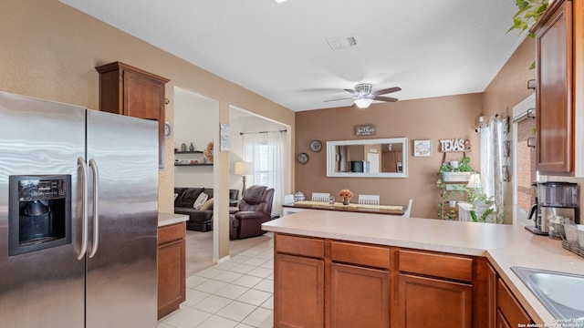 kitchen featuring kitchen peninsula, stainless steel refrigerator with ice dispenser, ceiling fan, sink, and light tile patterned floors