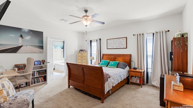 carpeted bedroom with ceiling fan, ensuite bathroom, and multiple windows