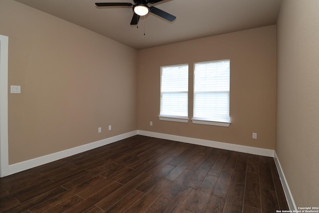 empty room featuring dark wood-style flooring, a ceiling fan, and baseboards