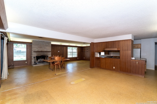 unfurnished living room with a textured ceiling, a fireplace, and wooden walls