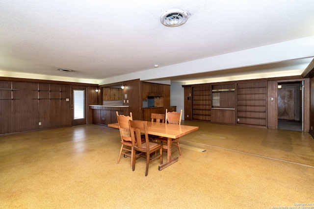 dining room with a textured ceiling and wooden walls