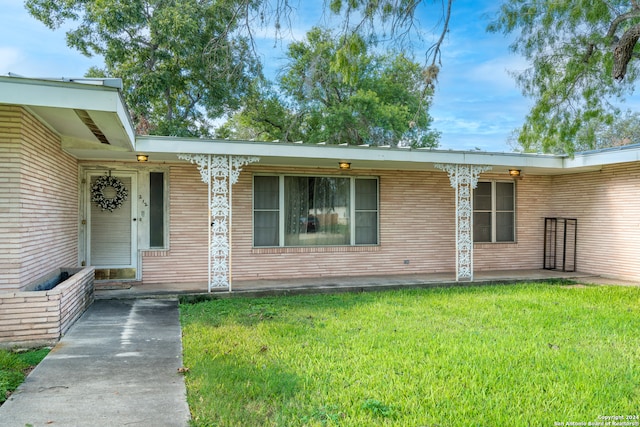 entrance to property with a lawn and covered porch