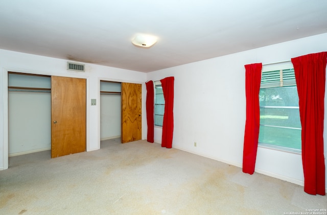 unfurnished bedroom featuring multiple closets and carpet floors