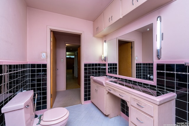 bathroom with tile walls, tile patterned floors, vanity, and toilet