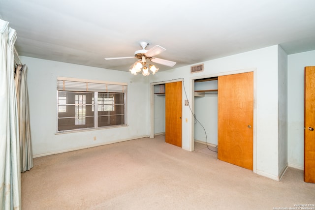 unfurnished bedroom with light carpet, ceiling fan, and multiple closets